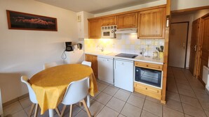 A compact kitchen with wooden cabinets, a microwave, a coffee maker, and a small oven. - Cozy 4-person apartment with balcony & garage in Samoëns (Samoëns)