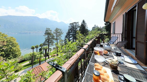 Een balkon met een ontbijttafel met uitzicht op een meer en bergen.