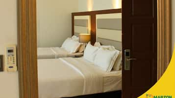 Habitación de hotel con dos camas, una mesita de noche con lámpara, teléfono y espejo sobre las camas.