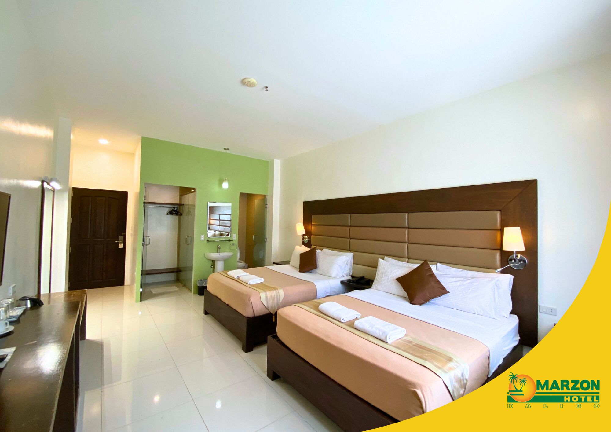 A hotel room with two beds, a bathroom, and a desk.