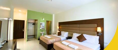A hotel room with two beds, a bathroom, and a desk.