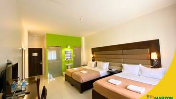 A hotel room with two beds, a desk, and a bathroom.