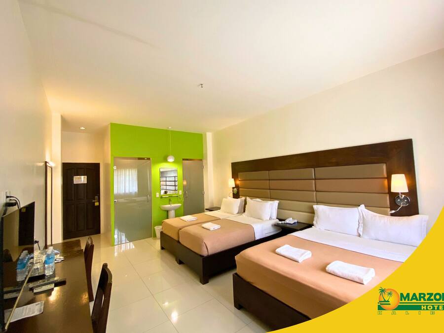 A hotel room with two beds, a desk, and a bathroom.