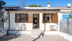 A house with a tiled roof, a front door, a small porch, and a satellite dish. - Pet-Friendly Apartment "Casa Museddu" with A/C, Terraces & Garden (Cardedu)