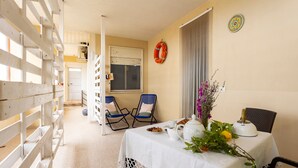 A room with a table set for breakfast, two chairs, a window with a curtain, and a door leading to another room. - Apartment 'Mare & Relax' near the sea with terrace and Wi-Fi (Menfi)