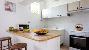 A kitchen with white cabinets, a wooden countertop, a microwave, a sink, and an oven. - Apartment 'Mare & Relax' near the sea with terrace and Wi-Fi (Menfi)