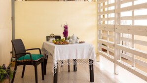 A dining area with a table set for two, a chair, and a decorative plant. - Apartment 'Mare & Relax' near the sea with terrace and Wi-Fi (Menfi)
