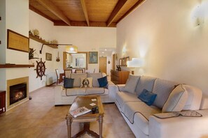 Una sala de estar con chimenea, sofás, una mesa de centro y techo de madera.