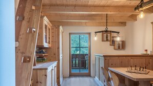 A wooden interior with a kitchen area, a dining table, and a view through a glass door to an outdoor deck. - Holiday Apartment "Ringelblume Biohof Unterspisser" with Mountain View, Balcony & Wi-Fi (Lajen)