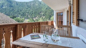 A wooden balcony with a table set for two, a book, and a water pitcher. - Holiday Apartment "Ringelblume Biohof Unterspisser" with Mountain View, Balcony & Wi-Fi (Lajen)