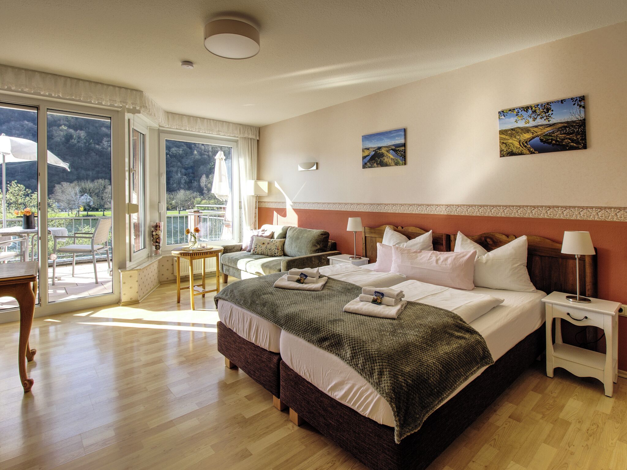 A bedroom with a large bed, a small table, a chair, and a view of a balcony.