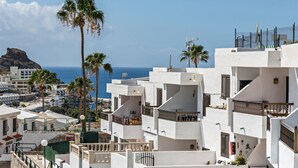 Zona residencial costera con edificios blancos, balcones y palmeras.