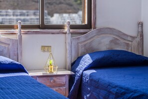 A bedroom with a wooden headboard, a bedside table with a lamp, and a window with a view.
