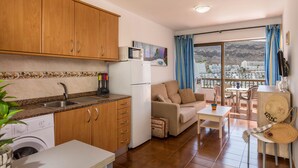 Un espacio habitable compacto con kitchenette, un sofá, una mesa de comedor y vistas a un paisaje montañoso.