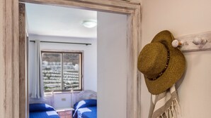 Una habitación con dos camas, una ventana con vistas y un sombrero colgado en la pared.
