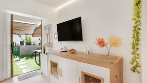 A modern kitchen with a wooden countertop, a mounted TV, and a view of a garden. - Apartment 'Esther Dream Bungallow' with Pool, Wi-Fi, A/C, Terrace & Garden (Mogán)