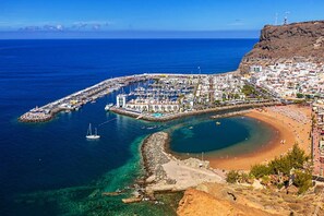 A coastal town with a marina, sandy beach, and rocky cliffs.