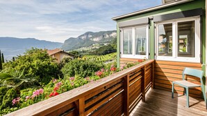 A balcony with a wooden railing, a chair, and a view of a mountainous landscape. - Apartment 'Kraidlhof - Designapartment Isabel' with Mountain View, Shared Pool & Wi-Fi (Kurtatsch)