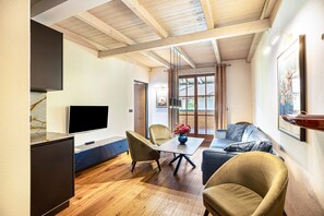 Una sala de estar moderna con un televisor de pantalla plana, una mesa de comedor con sillas, un sofá y un ventanal con cortinas.