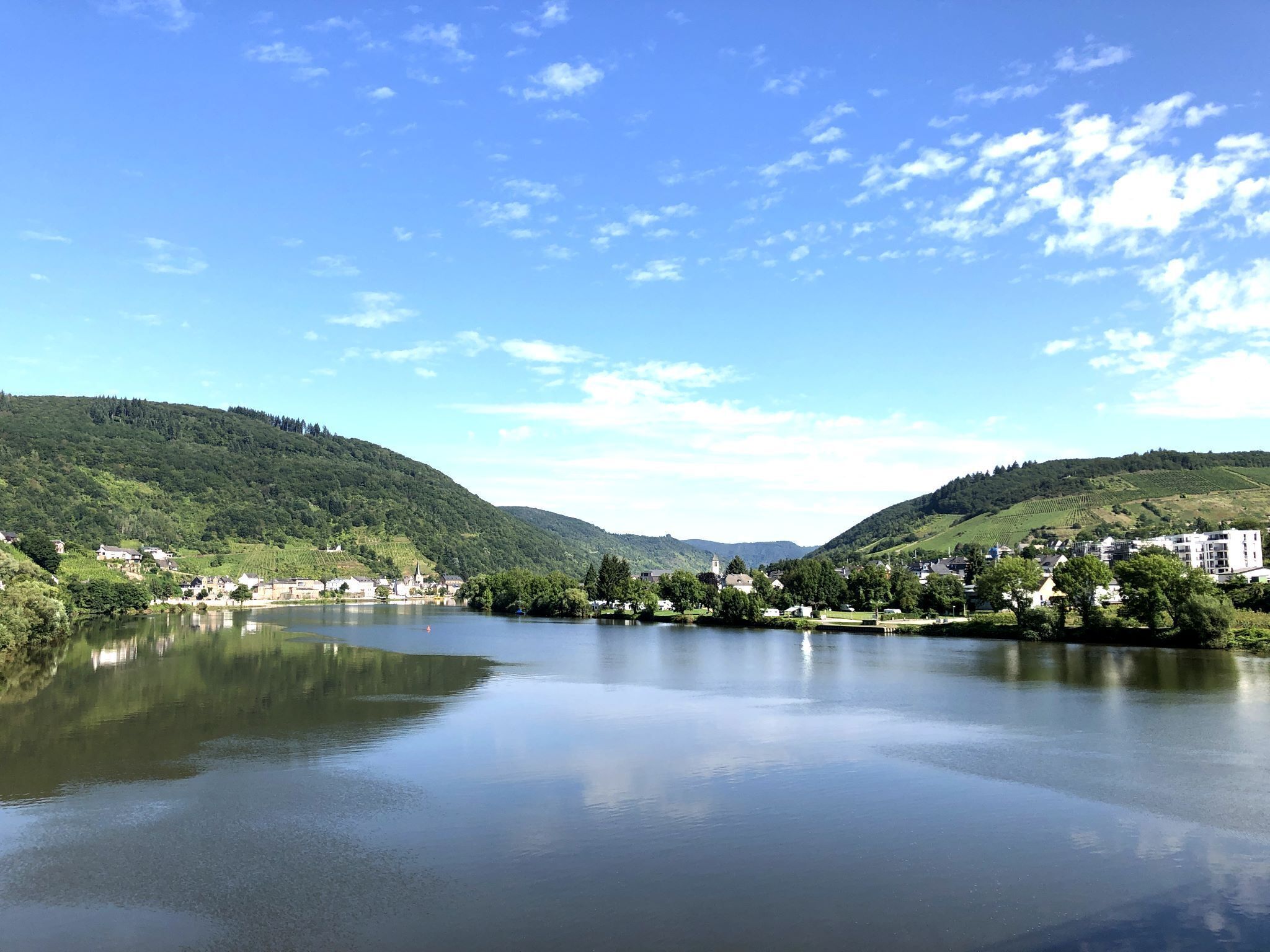 A calm lake with surrounding hills and a small town.