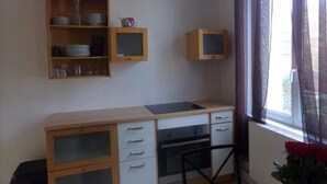 A compact kitchen with a built-in oven, a small sink, and a window with curtains.