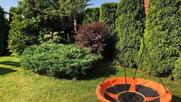 Un jardin avec une balançoire et divers arbustes.