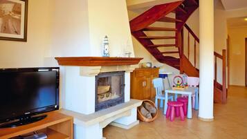 Un salon avec une cheminée, un téléviseur et un escalier.