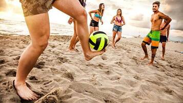 Une scène de plage où des gens jouent au volleyball.