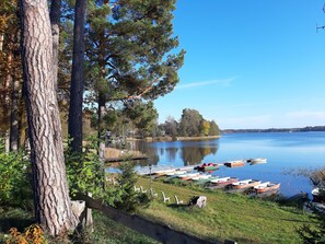 Un lago tranquillo con barche ormeggiate sulla riva, circondato da alberi e un'area verde.