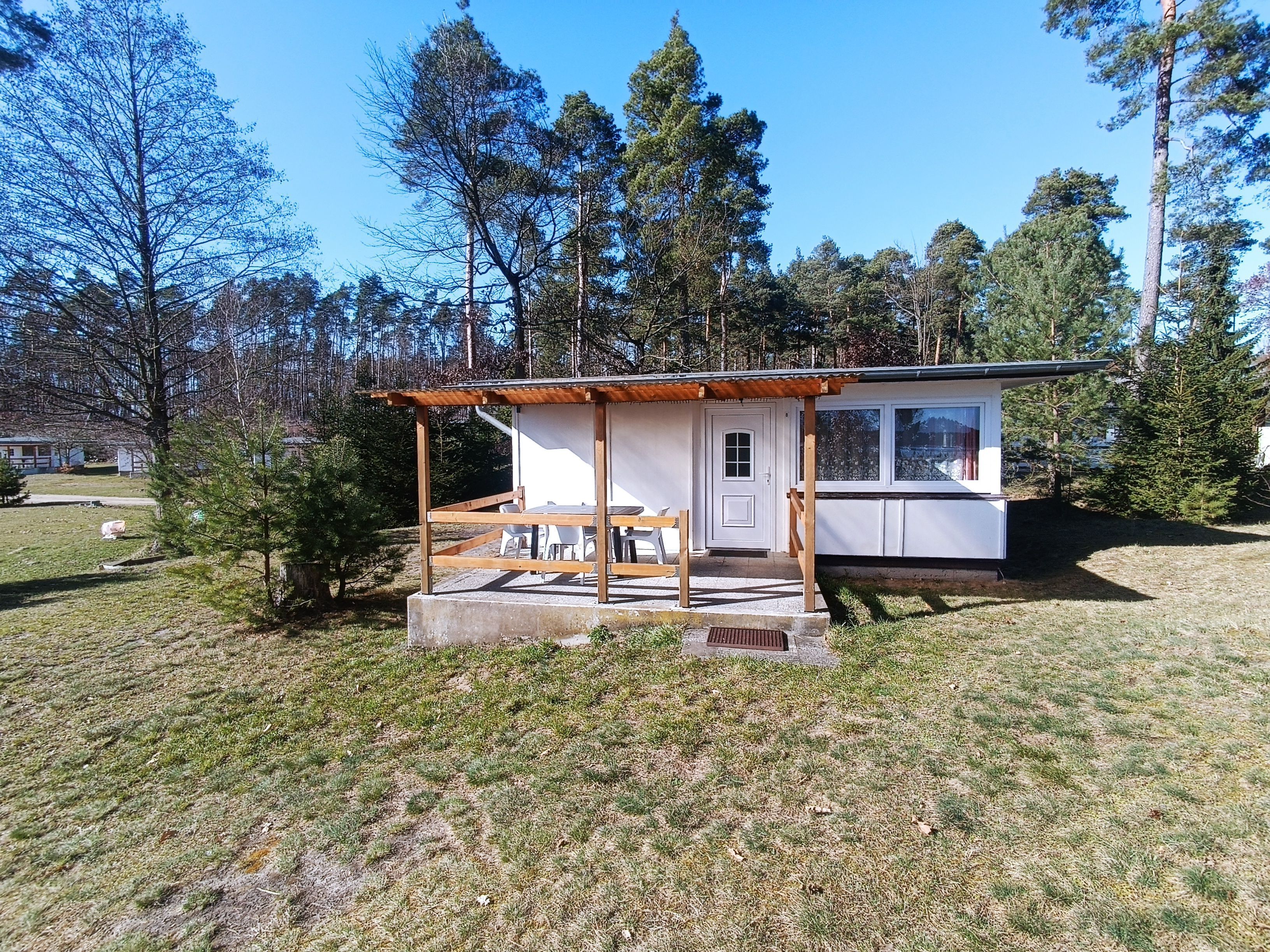 Uma cabana pequena com varanda de madeira e mesa com cadeiras.