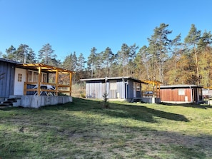En campingplads med flere træhytter, et overdækket picnicområde og et lille udhus.