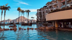 A resort pool with rock formations, palm trees, and a mountain in the background. - Villa La Estancia Unit # 2805 - B side Jr studio 2Q Beds Beach lux front resort. (Cabo San Lucas)