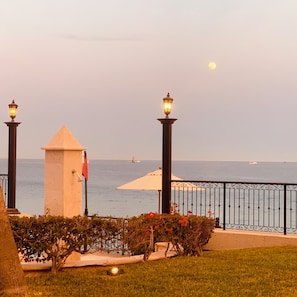 A coastal promenade with a lamp post, a flag, and a view of the sea.