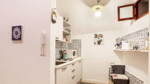 Een compacte keuken met witte kastjes, een magnetron, een koffieapparaat en een klein spoelgedeelte.