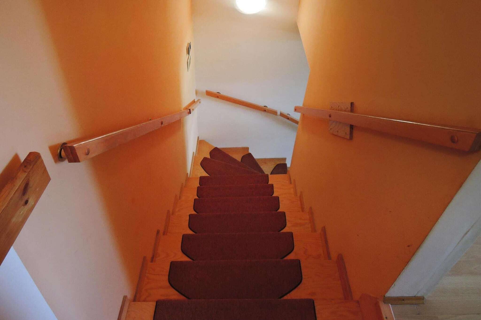 A wooden staircase with a handrail, leading to a landing.