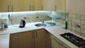 A kitchen with wooden cabinets, a sink, a stove, and a coffee maker.