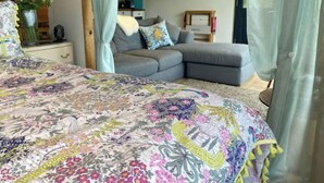Ein Schlafzimmer mit einem großen Bett, einem grauen Sofa und einem hölzernen Kopfende.