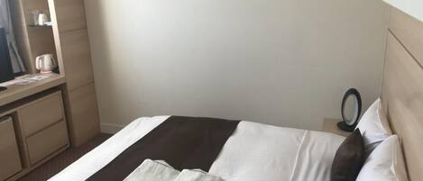 A neatly made bed with a brown and white striped bedspread, a white pillow, and a folded white towel.