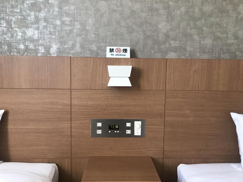 Ein Hotelzimmer mit einem hölzernen Kopfteil, einem Nachttisch und einem Schild, das ein Rauchverbot anzeigt.
