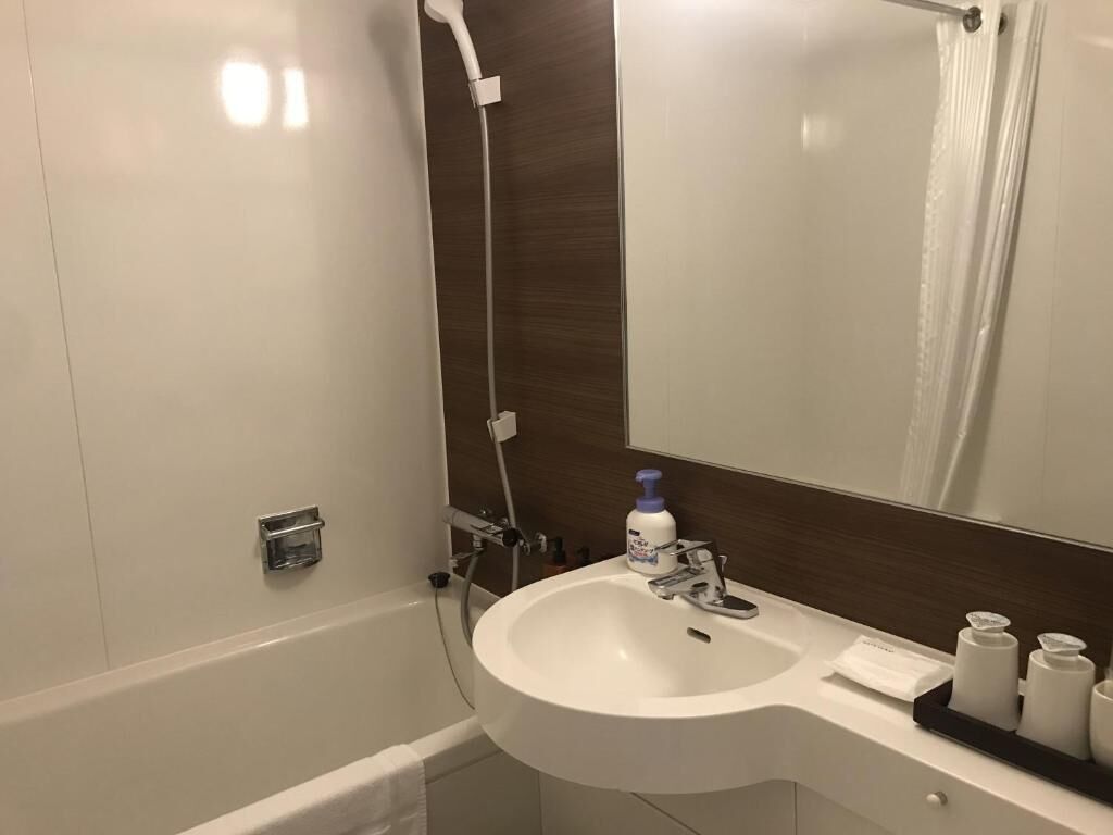 A modern bathroom with a white sink, a mirror, and a shower.