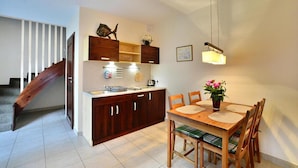 Une cuisine compacte avec des meubles en bois, une table à manger avec des chaises et un escalier menant à un autre niveau.