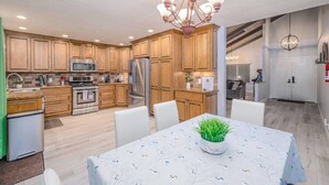A modern kitchen with wooden cabinets, stainless steel appliances, and a dining area with a table set for two.