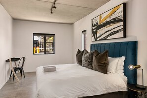 Quarto moderno com cama grande, escrivaninha e janela.