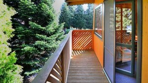 Una terraza de madera con un ventanal de vidrio que da a una habitación.