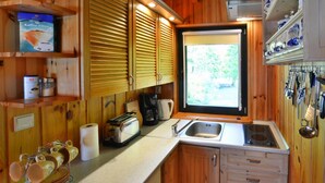 Una cocina compacta con armarios de madera, un lavamanos integrado y un ventanal que proporciona luz natural.