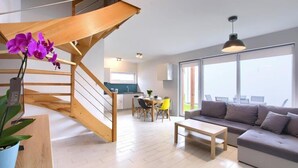 Un salon moderne avec un escalier, un coin repas et de grandes fenêtres.