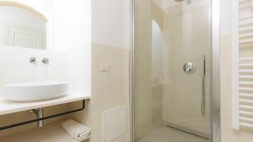 A modern bathroom with a glass-enclosed shower, a white sink, and a towel rack.