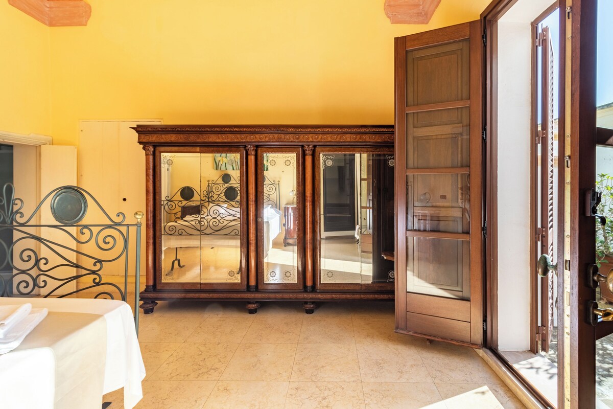 A room with a wooden cabinet, a bed, and a table with a white tablecloth.