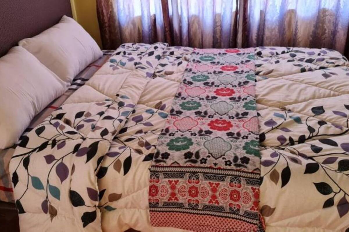 Ein Bett mit einer floralen Steppdecke und zwei Kissen.