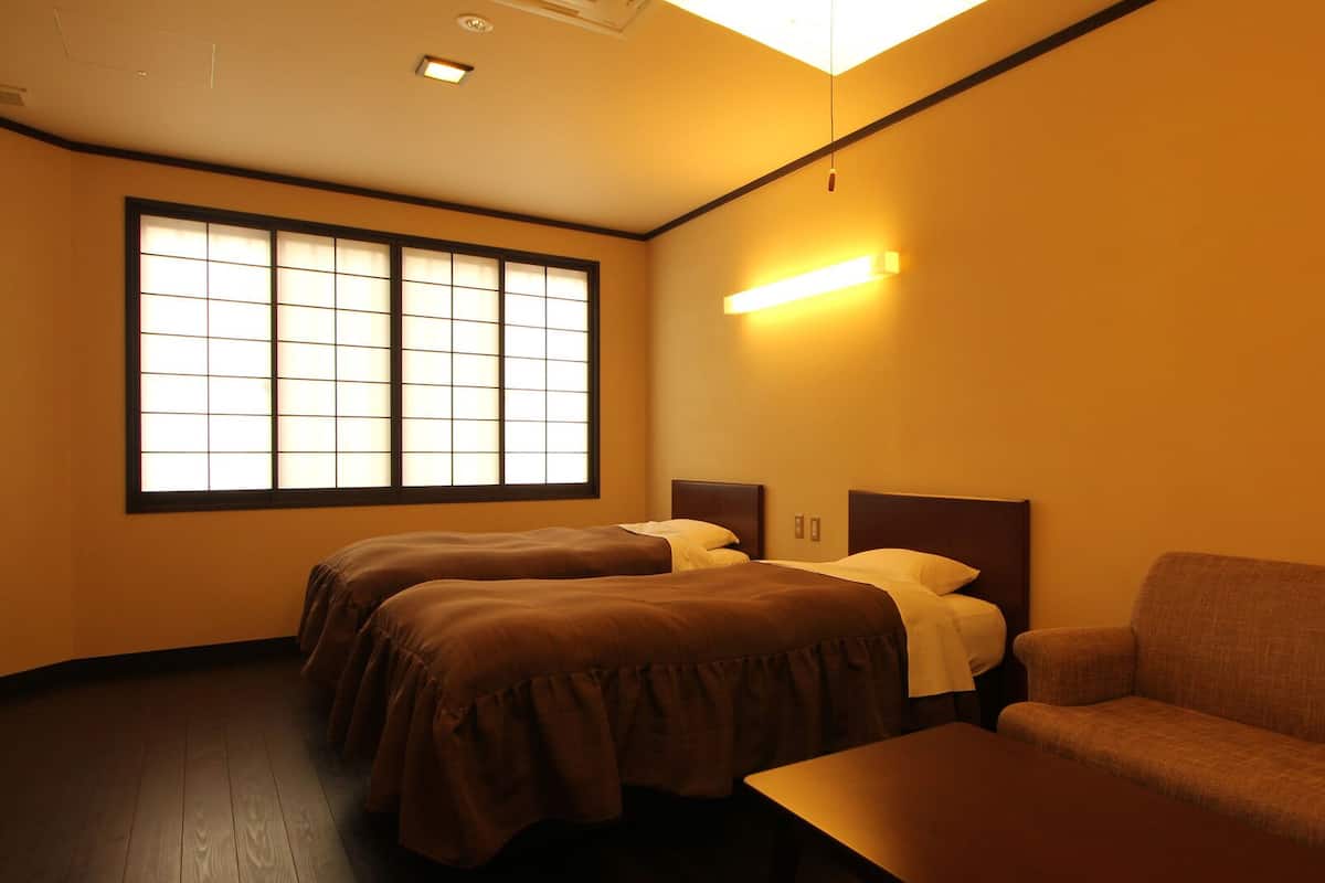 A hotel room with two beds, a sofa, and a large window.